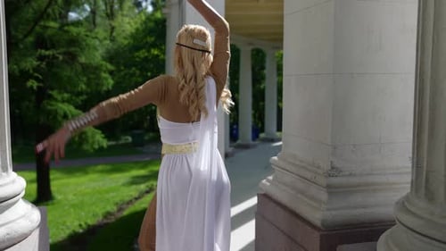 une blonde dans un chiton grec danse parmi les colonnes