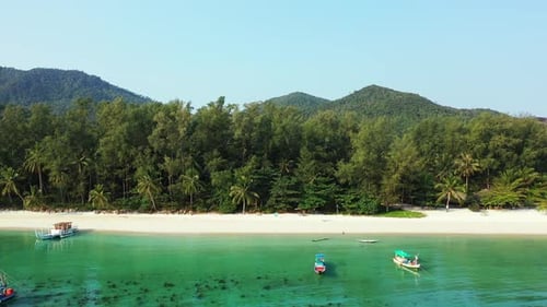 Peaceful vacation bay with calm turquoise lagoon full of fishing boats near white sand of exotic bea