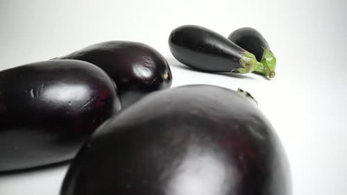 Fresh, Shiny Eggplants on a White Surface