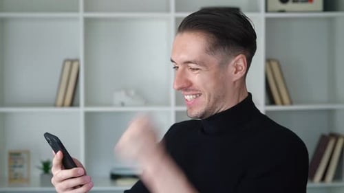 Man Excitedly Checks Mobile Phone in Modern Interior