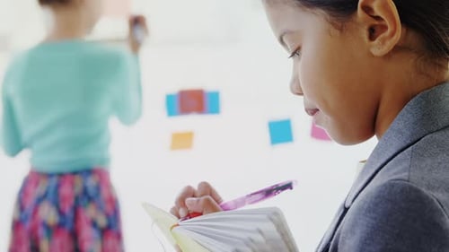 Child Writes in Notebook During Meeting