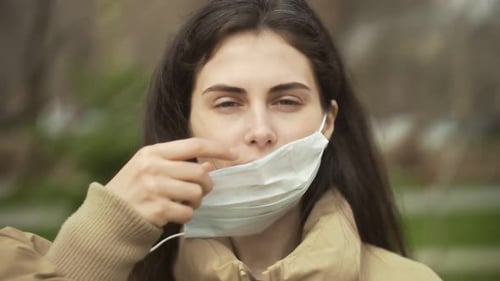 Woman Puts on Surgical Mask Outside
