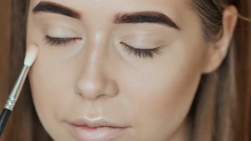 Woman Applying Makeup to Her Face with Brush