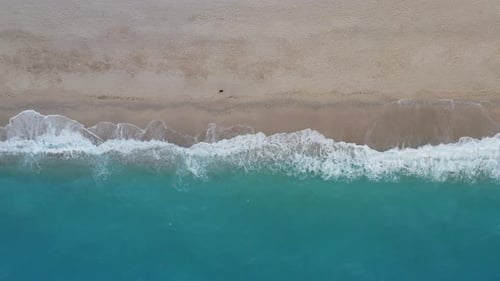 Top Down View of Sandy Beach and Turquoise Sea Waves at Shore Edge