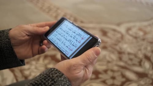 Man Reading Arabic Script on Smartphone