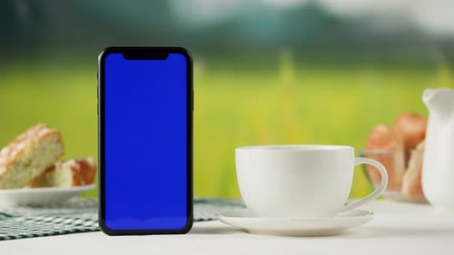 Smartphone with Blue Chroma Key Screen and Tea Cup Closeup