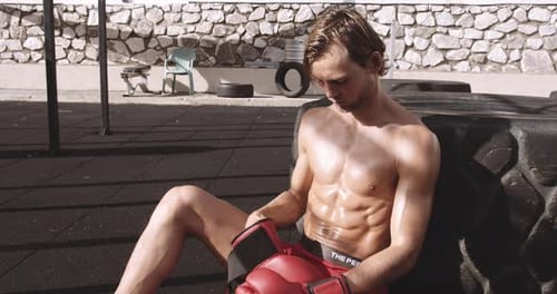 Muscular Man with Boxing Gloves Training Outdoors