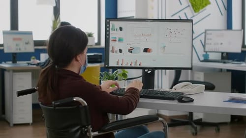 Femme d'affaires avec masque facial immobilisée en fauteuil roulant travaillant au projet
