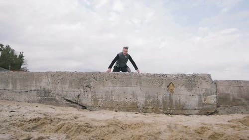 Young Man Doing Parkour Tricks on the Beach Near the Sea