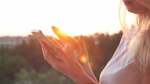Woman Uses Mobile Phone During Golden Hour