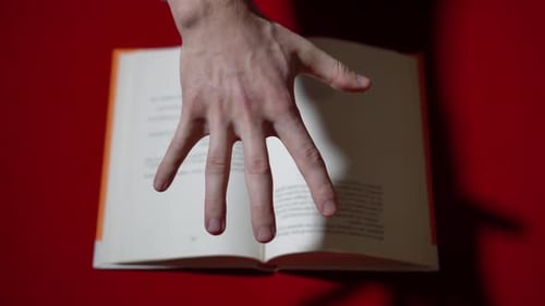 Hand Turning Pages of Open Book