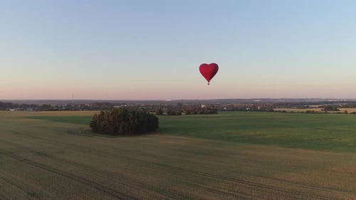 Heart Shaped Hot Air Balloon Flying Over Green Fields