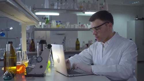 Scientist Works on Laptop in Bright Laboratory