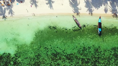 Long tail boats anchoring on white sandy shore of tropical island with exotic beach washed by turquo