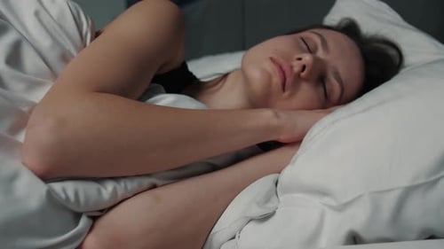 Close Up Portrait of Relaxed Woman Sleeping on a White Pillow in Bed. Portrait of Young Caucasian