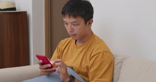 Man Using Smartphone Device While Sitting on Sofa