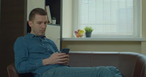 Young Adult Using Phone Indoors on Sofa