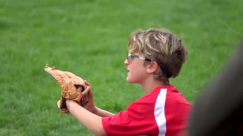A boy practices playing catch on a little league baseball field.