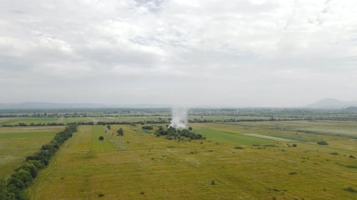 Aerial Flight People Burn Dry Grass in the Fields. Fire in the Field and Flying Over a Smoky Field.