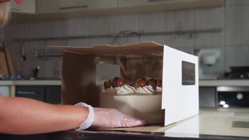 Woman Boxes Delicious Frosted Cake in Kitchen