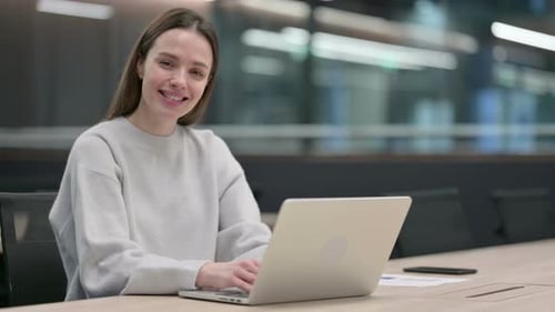 Smiling Woman Works on Laptop in Modern Office