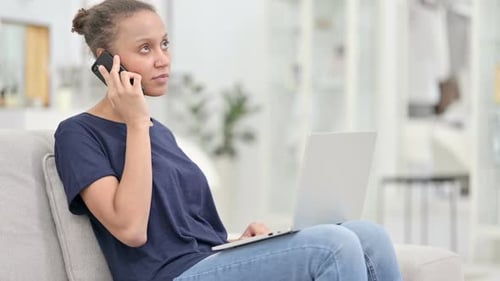 Woman Talking on Phone While Using Laptop at Home