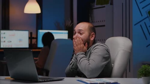 Glücklicher, fröhlicher Geschäftsmann lächelt beim Blick auf das Laptop-Computerdisplay
