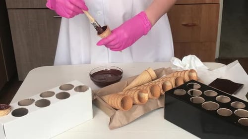 Confectioner Painting Pastry Cones with Chocolate