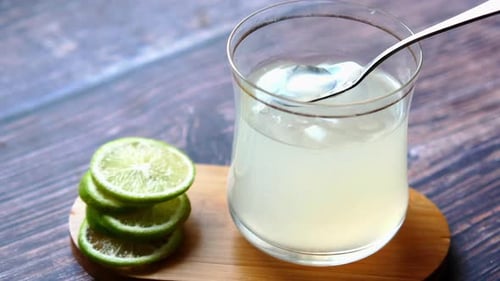 Refreshing Lemonade with Lime Being Stirred with Spoon