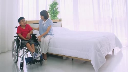 Boy in Wheelchair with Woman Beside Hospital Bed