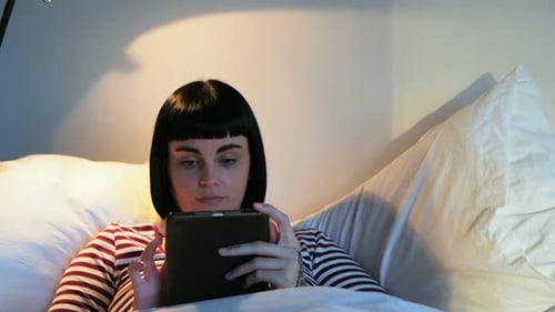 Woman Using Tablet in Bed at Night