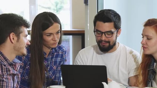 Group of Friends Using Laptop at the Coffee Shop While Having Breakfast