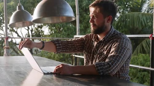 Bonito homem barbudo abrindo laptop e começando a trabalhar ao ar livre