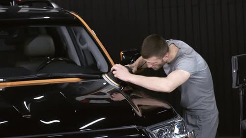 Man Polishing Black Car in Garage