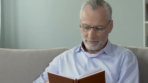 Senior Man Reading a Book on Sofa