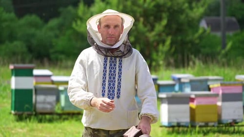Beekeeper on apiary. Portrait of smiling man on outdoor hives background.