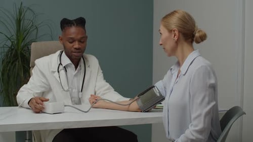 Doctor Measures Blood Pressure of Woman in Clinic
