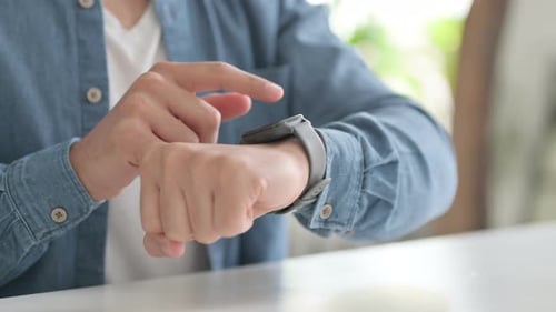 Man Using Smart Watch Technology at Table