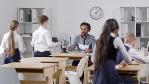 Primary School Pupils Submitting Answer Sheets to Black Teacher