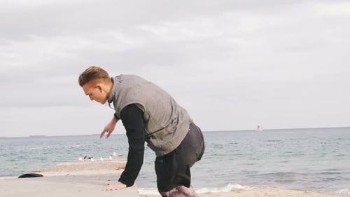 Young Man Doing Parkour Tricks on the Beach Near the Sea