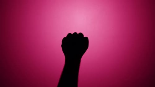 Hand Silhouette makes a Fist against Pink Background