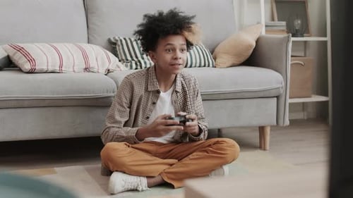 African Boy Playing Videogame on Floor