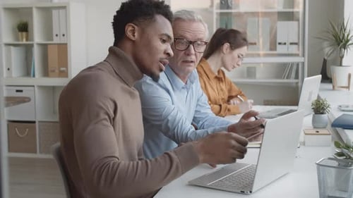Office Workers Collaborating on Laptop in Modern Workplace