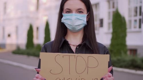 Woman in Face Mask Holding Protest Sign
