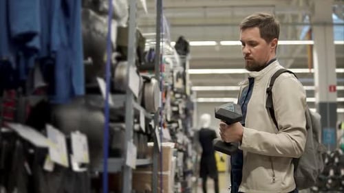 Bearded Man is Holding Dumbbell in a Hall of Sport Store Checking Weight