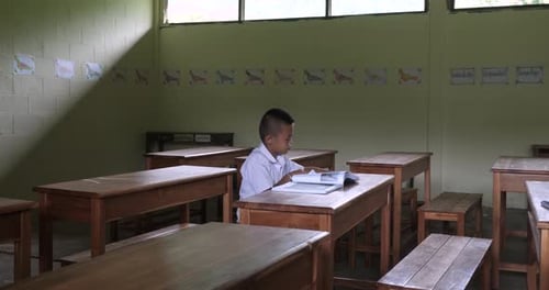 Diligent Student Reads Book in Empty Classroom