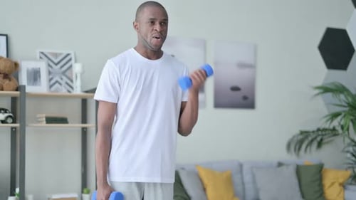 Man Lifts Dumbbells for Strength Training at Home