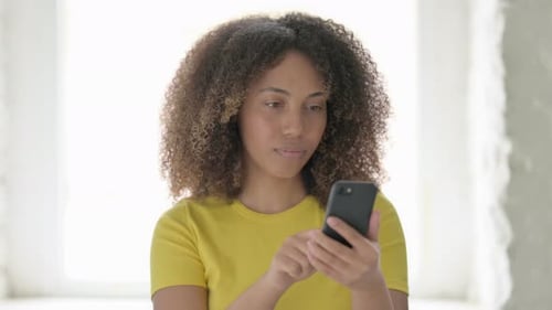 African Woman Reacting to Loss on Smartphone