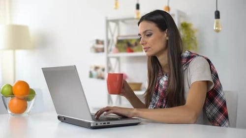 Woman Working on Laptop at Home Drinking Coffee