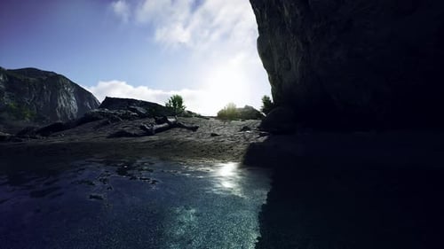 Sandstrand in einer Bucht, umgeben von steilen Bergen bei Sonnenuntergang